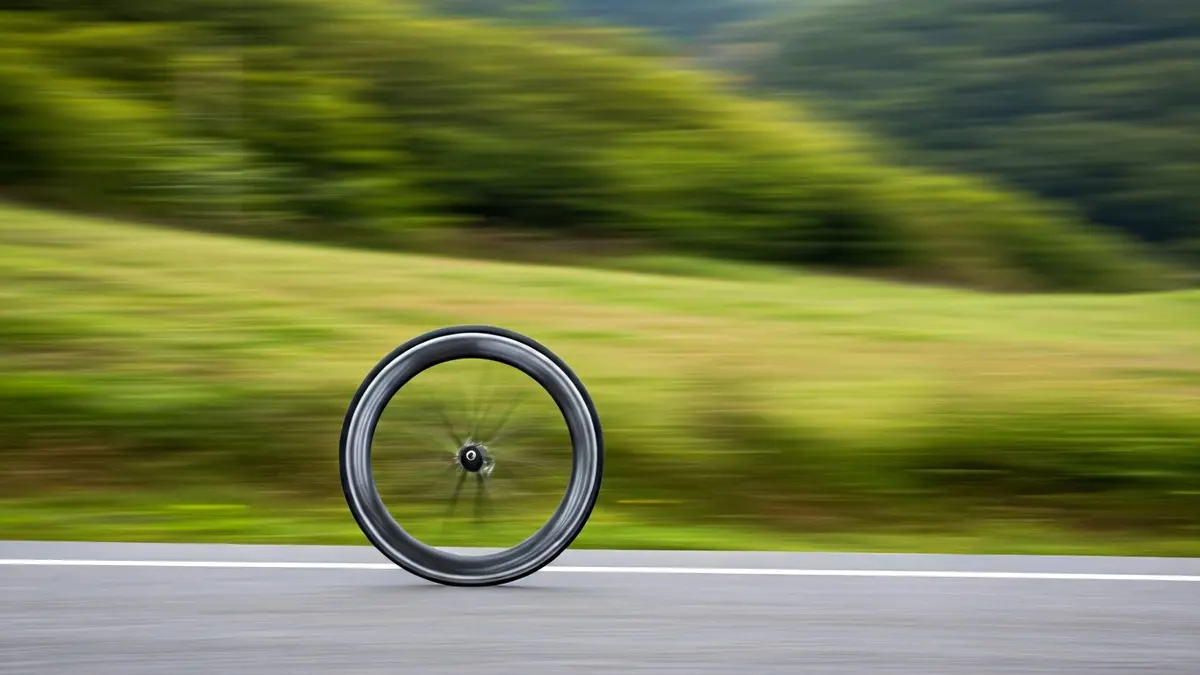Imagen genérica de una rueda de bicicleta en una carrera, con el paisaje verde vasco de fondo.