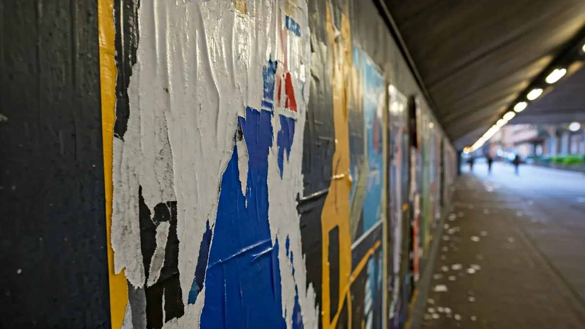 Generic image of a torn poster in a pedestrian underpass, suggesting an act of vandalism.