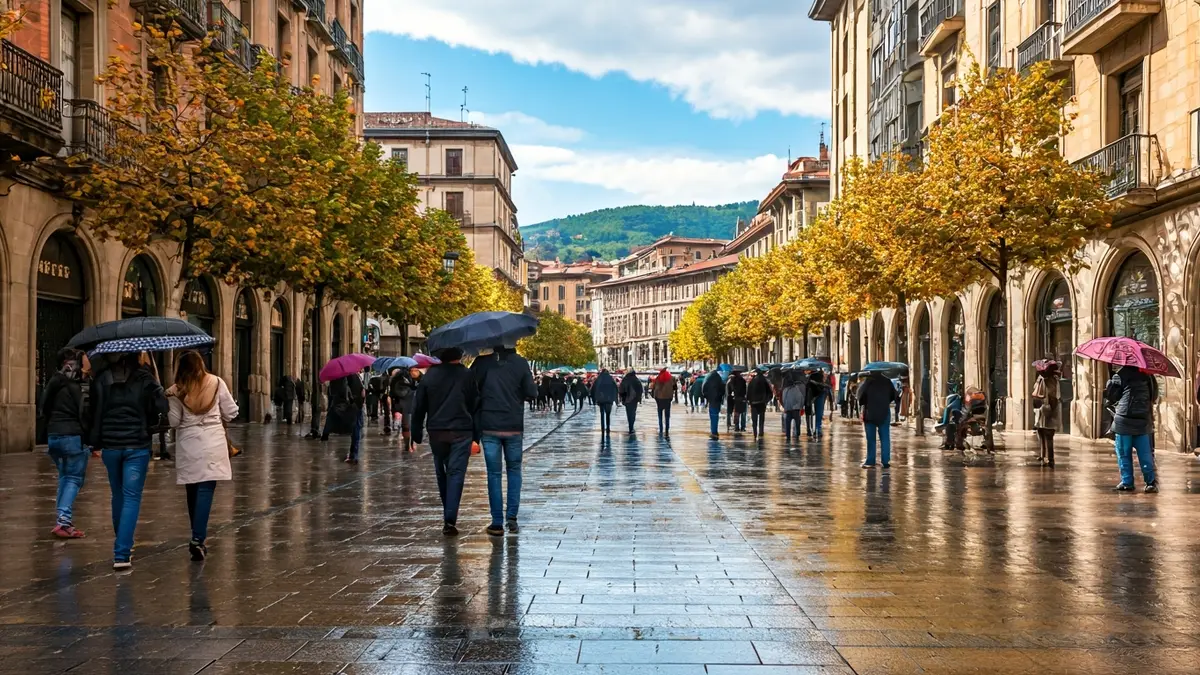 Bilboko kale baten irudia, eguzkitsua eta euri-girokoa, eguraldi aldaketa nabarmena erakutsiz.