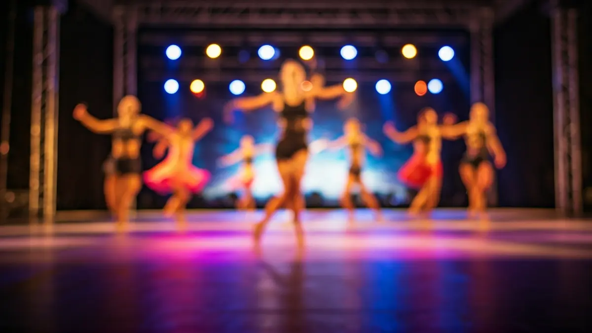 Imagen genérica de un escenario de competición de danza moderna, con luces de colores y bailarines difuminados.