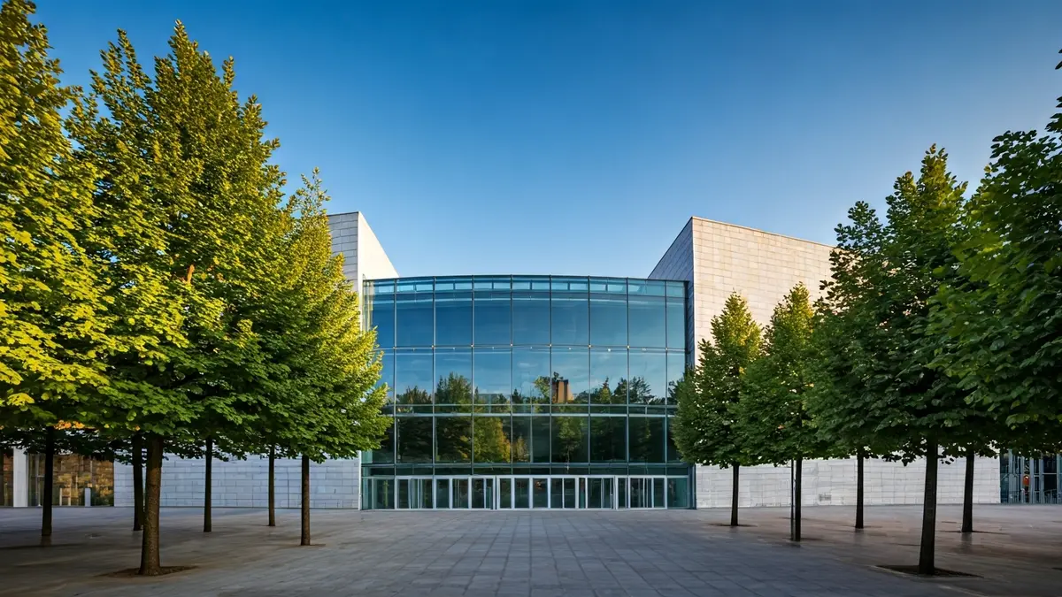 Imagen exterior del museo de la ciencia Eureka, con grandes paneles de cristal y árboles verdes.