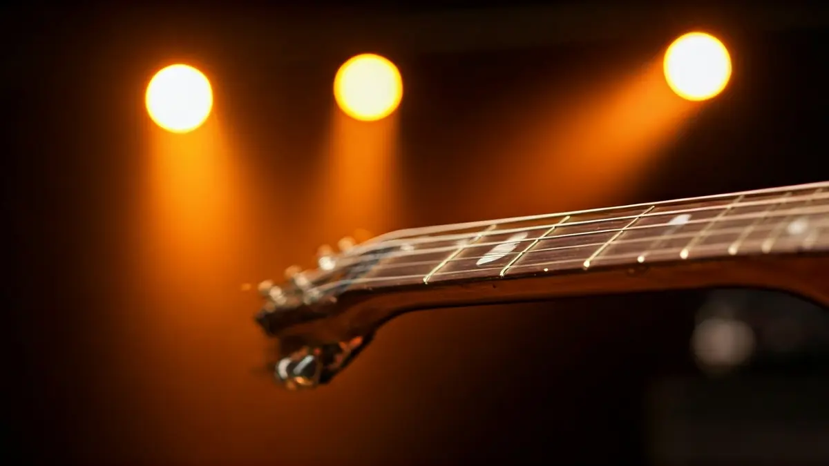 Imagen genérica de un diapasón de guitarra heavy metal con luces de concierto borrosas.