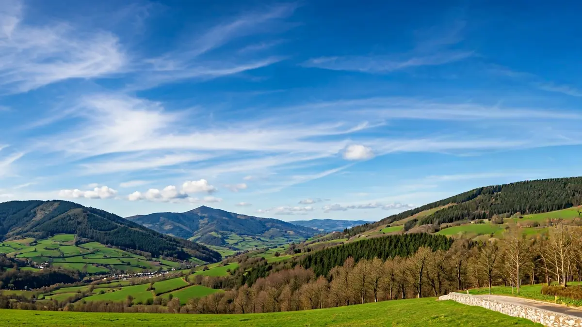 Irudi generikoa Euskal Herriko paisaia menditsu berde baten zeru garbiarekin eta hodei sakabanatuekin.