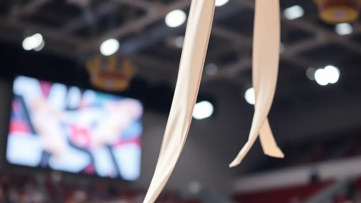 Irudi generikoa gimnasia erritmikoko zinta bat mugimenduan, lehiaketa-areto baten atzealde lausoarekin.