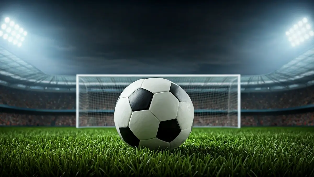 Generic image of a soccer ball on grass, with a blurred goal net in the background.