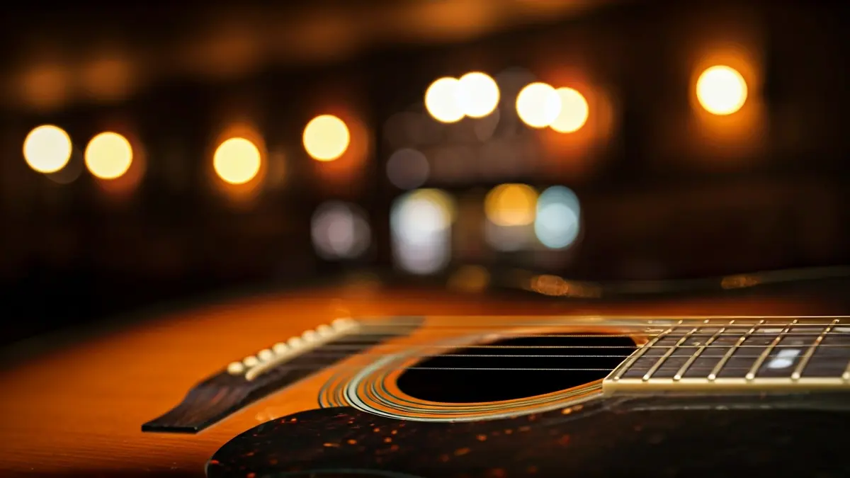 Irudi generikoa blues gitarra akustiko baten zuloaren eta soken hurbileko plano batena, atzealde lauso batekin.