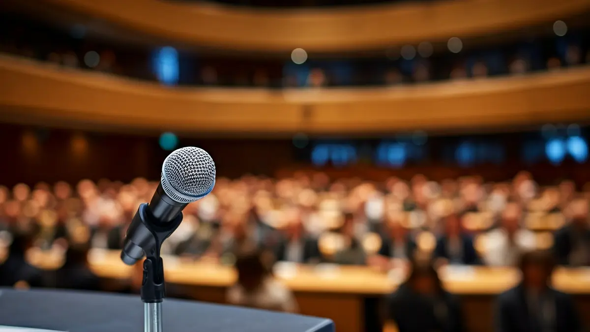 Imagen genérica de un micrófono en un podio, en una sala de conferencias.