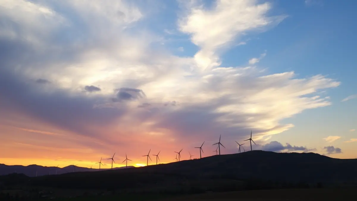 Generic image of wind turbines on a mountain ridge at sunset, with a dramatic sky and a rural landscape.