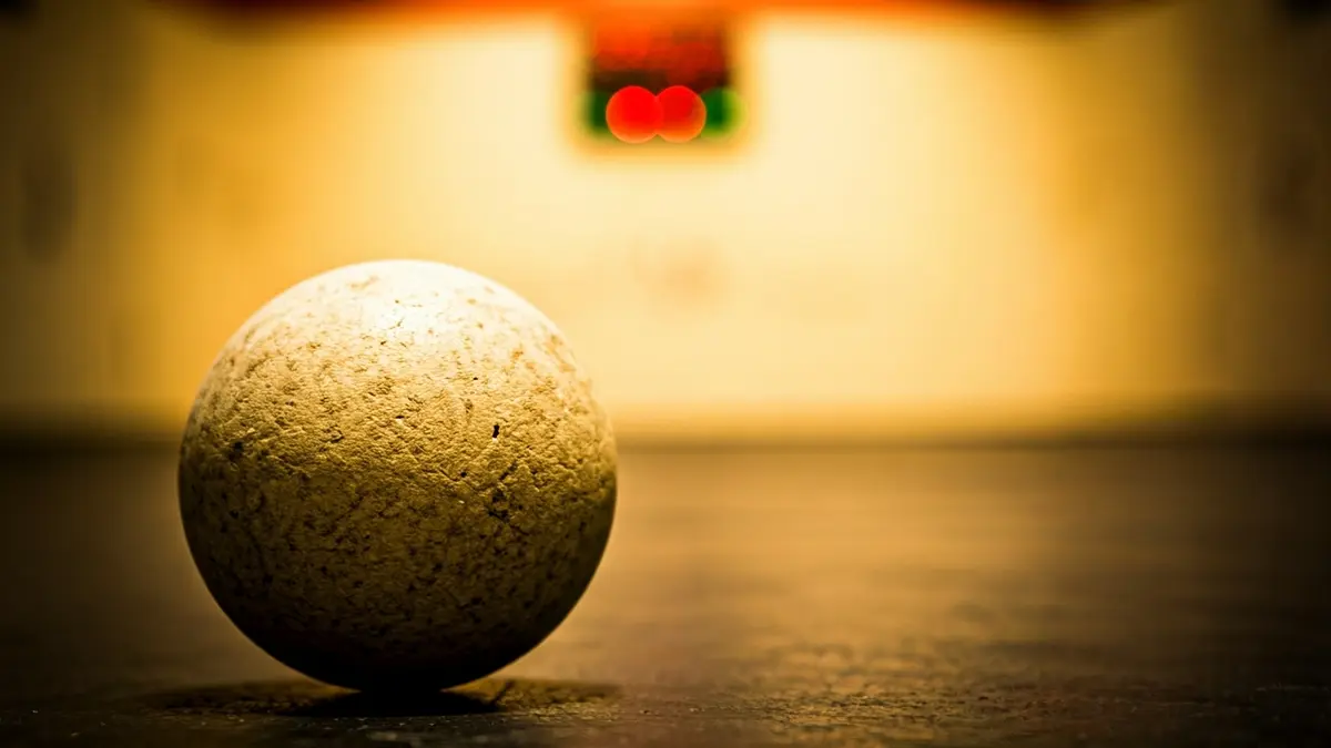 Generic image of a cesta punta ball on the court, with a blurred fronton in the background.