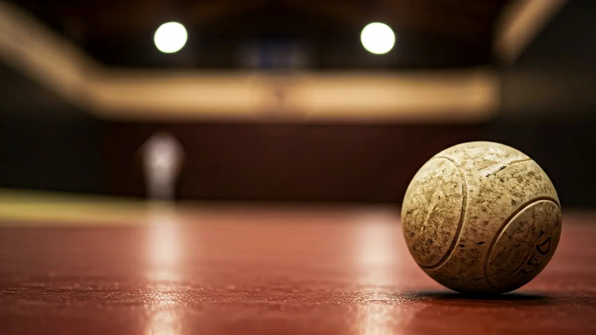 Handball resting on the fronton wall, with blurred court lines in the background.