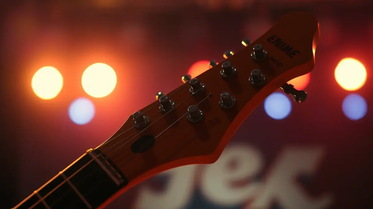 Generic image of a vintage electric guitar headstock with tuning pegs, blurred stage lights in the background, evoking a rock concert atmosphere.