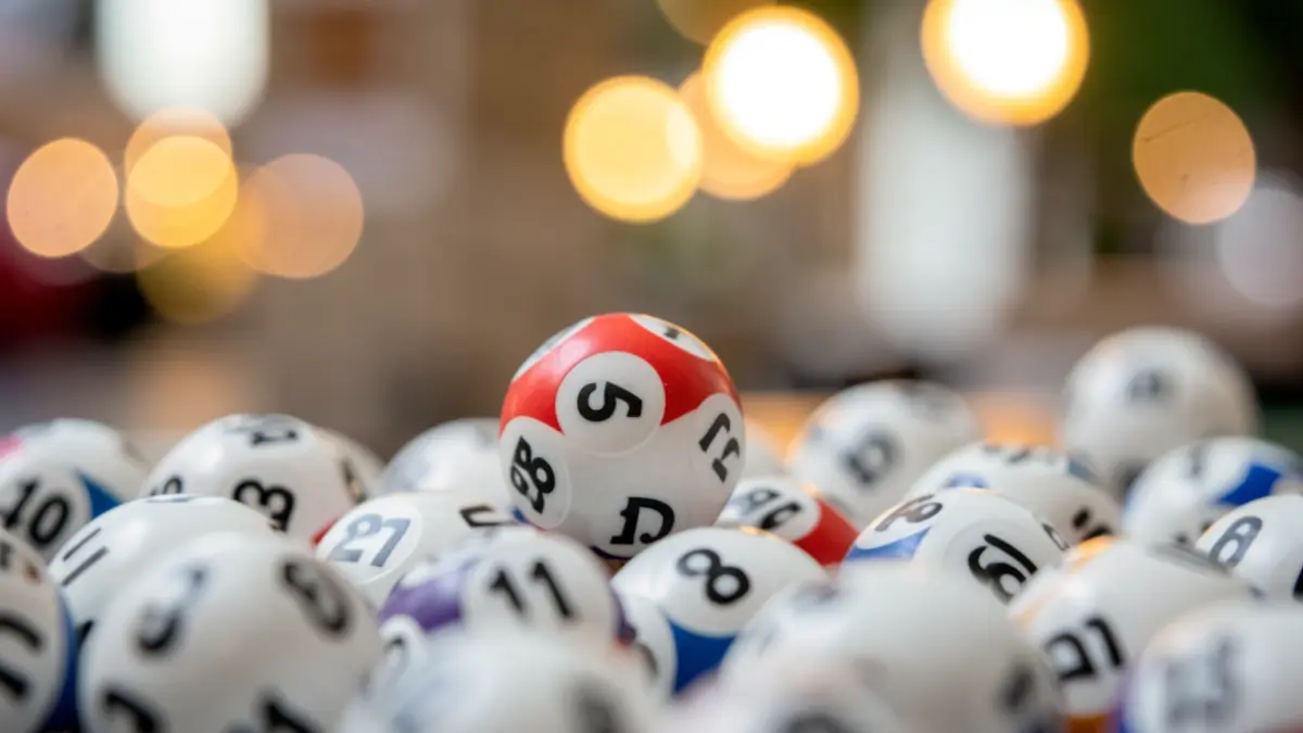 Close-up of lottery balls with numbers, one ball slightly separated, soft focus background with blurred lights, representing a lottery win.