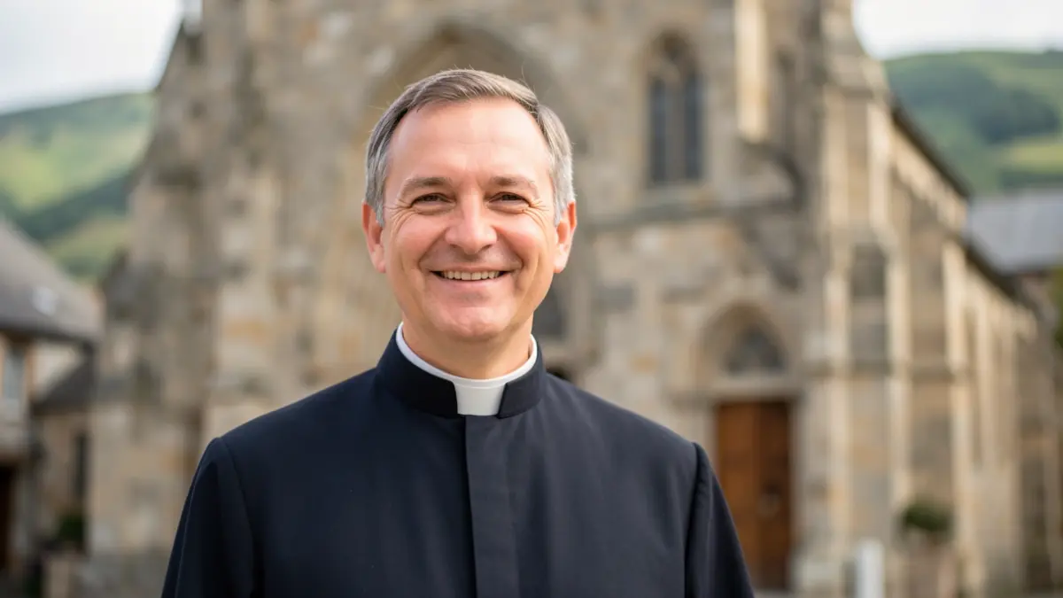 A friendly and approachable priest, in his cassock, in front of a Basque Country church.
