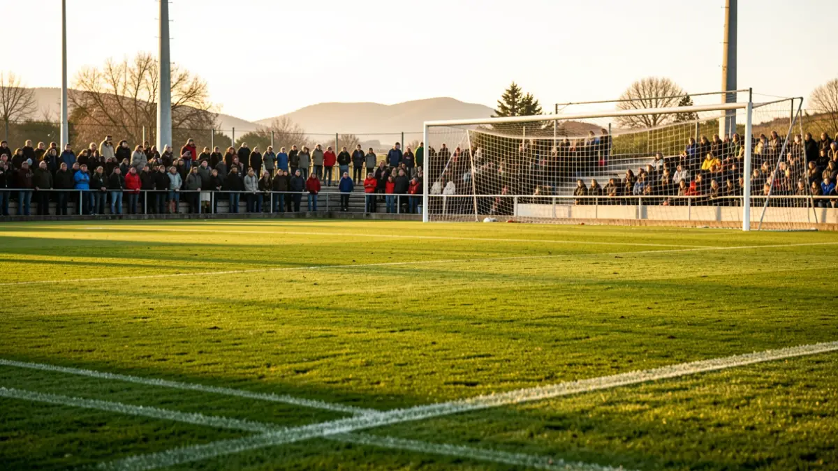 Un campo de fútbol en el País Vasco con césped verde y líneas blancas, una red de portería al fondo, bañado por la cálida luz del atardecer.