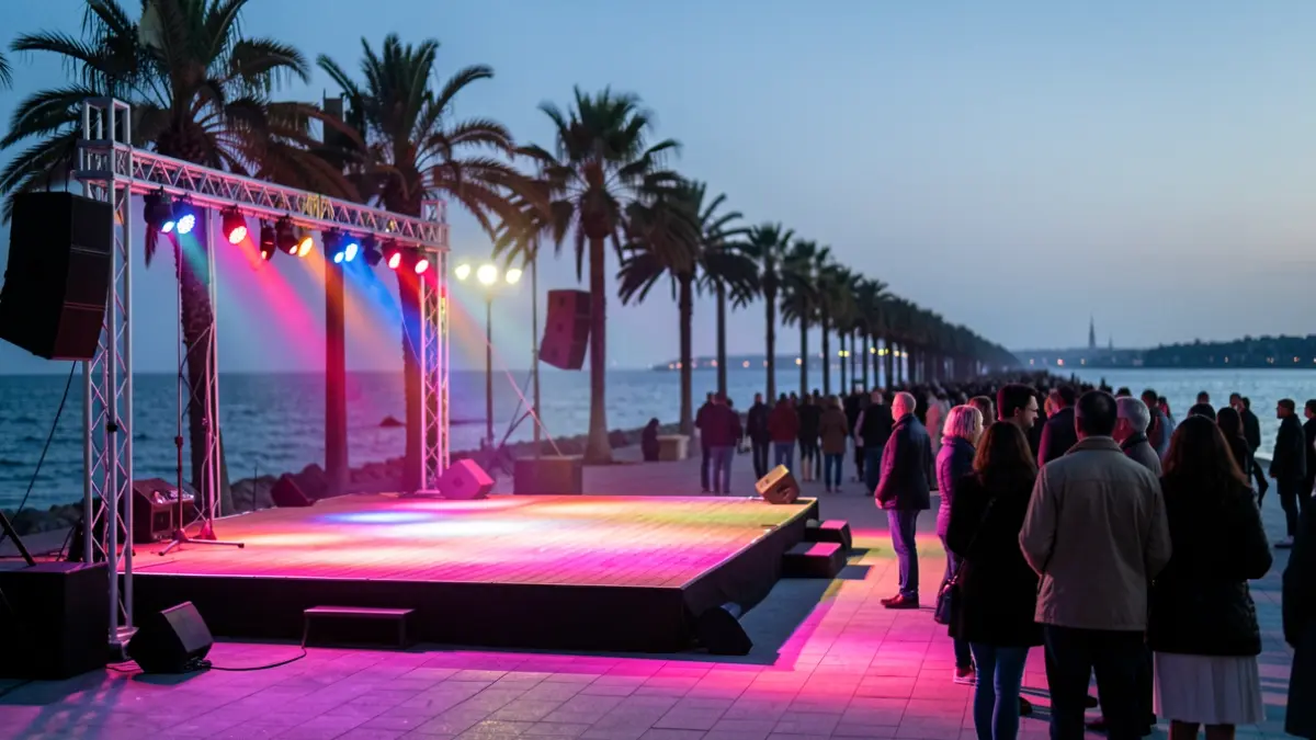 An outdoor stage on a promenade at sunset, by the sea.
